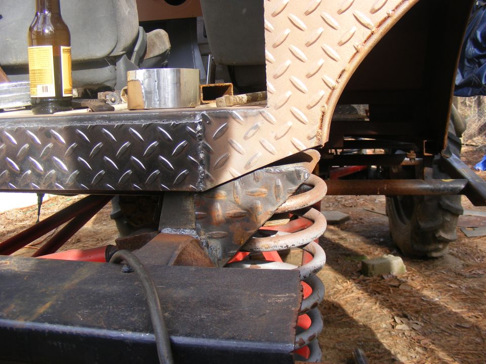 Diamond plate fender flare and suspension components with a beer bottle on a workbench