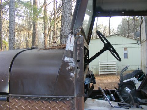 View of an old vehicle's interior showing the steering wheel, dashboard, and part of the hood. Diamond plate i