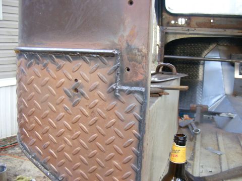 Diamond plate metal panel on a vehicle interior, with a beer bottle and tools visible