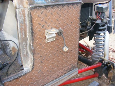 Close-up of diamond plate panel on a custom off-road vehicle, showing suspension and wiring