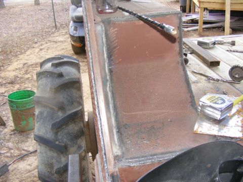 Tractor fender section with visible welds and a large tire in the background