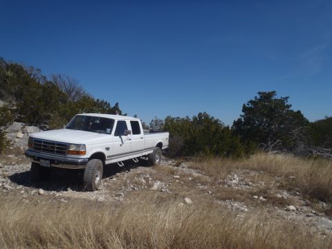 1997 Ford F-350 - This white 1997 Ford F-350 crew cab pickup truck is parked on a rocky, grassy hill under a clear blue sky.