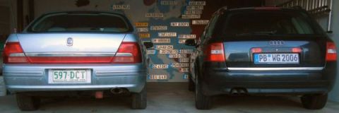 1999 Ford Fairlane - Two vehicles are parked indoors, with a map of license plates on the wall behind them.