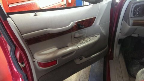 2000 Mercury Grand Marquis - Interior door panel of a 2000 Mercury Grand Marquis, showing wood trim and controls.