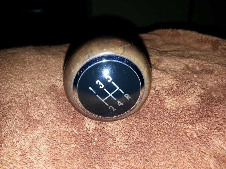 Wooden gear shift knob with a 5-speed manual pattern (1, 3, 5, 2, 4, R) on a brown textured surface
