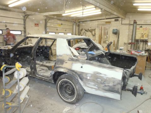 2001 Ford Crown Victoria - A car undergoing bodywork in a workshop, with tools and supplies visible.
