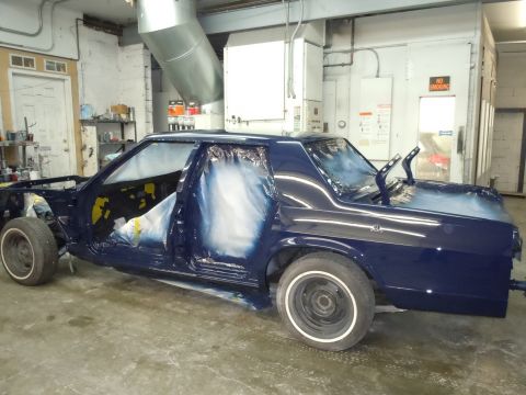 2001 Ford Crown Victoria - A dark blue 2001 Ford Crown Victoria is being prepped for paint in a workshop, with its doors open and taped.