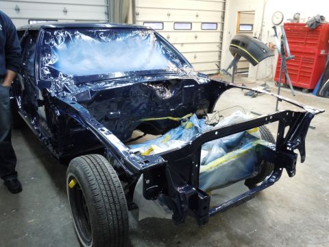 2001 Ford Crown Victoria - Car body undergoing paintwork in a workshop, with windows covered and engine bay prepped.