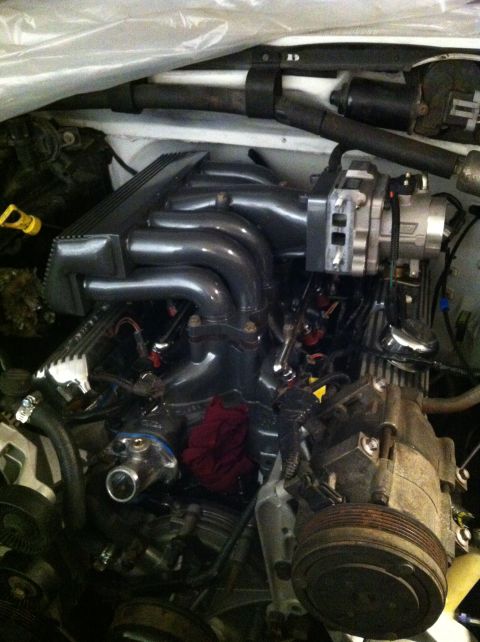 1992 Ford Bronco - Close-up view of an engine bay, likely modified, showing an aftermarket intake manifold and various engine components.