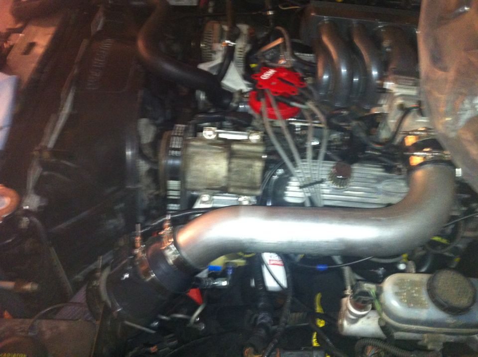 Engine bay with a red distributor cap and silver intake pipe