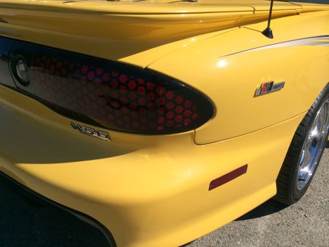 1968 Ford Mustang - Close-up of the rear of a yellow Pontiac Firebird, showing the distinctive taillight and badging.