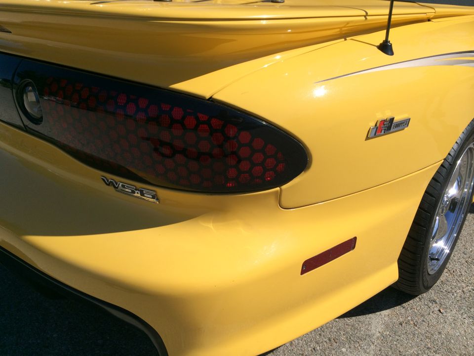 Rear quarter panel of a yellow Pontiac Firebird with WS6 and Ram Air badges