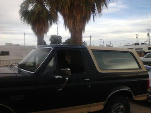 1990 Ford Bronco - Side profile of a black 1990 Ford Bronco with a tan removable top.