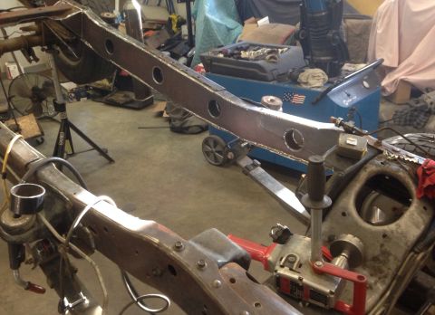 1993 Ford Bronco - The frame of a vehicle is being worked on in a workshop setting, with various tools and equipment visible.