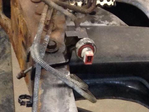 1993 Ford Bronco - A close-up view of automotive wiring and a sensor attached to a metal frame.