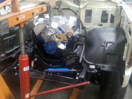 1982 Ford Bronco - Engine bay during installation with an engine hoist and a V8 engine.