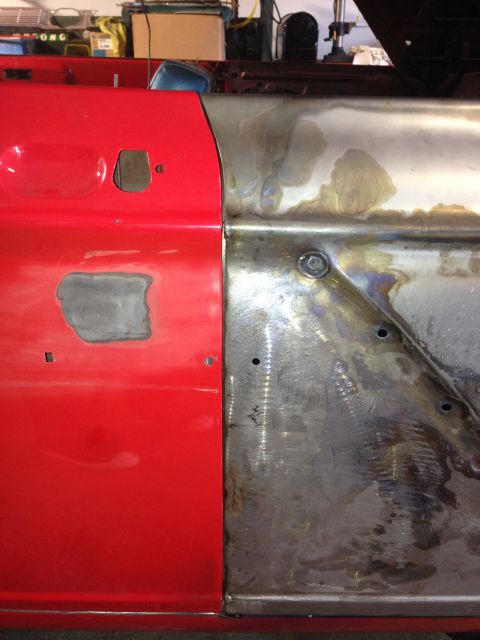 1964 Ford Fairlane - Close-up of a red car door panel showing a repair area with bare metal, welds, and a bolt.