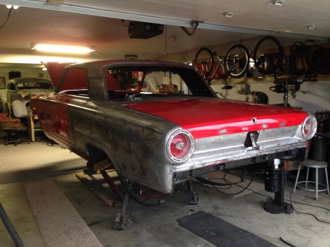 1964 Ford Fairlane - A classic car is being worked on in a garage, with another vehicle in the background.