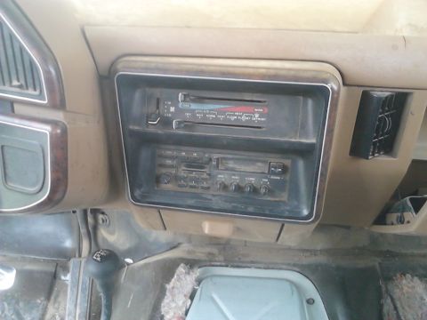 1990 Ford Bronco - The dashboard features an aftermarket radio and climate controls, with a gear shifter visible below.