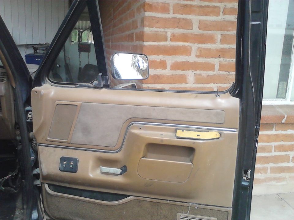 Interior of a car door showing the panel, handle, and mirror. The door is open