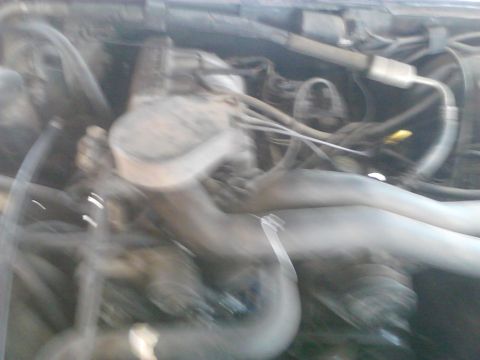 1990 Ford Bronco - The engine bay of a vehicle is shown, with various hoses and wiring present.