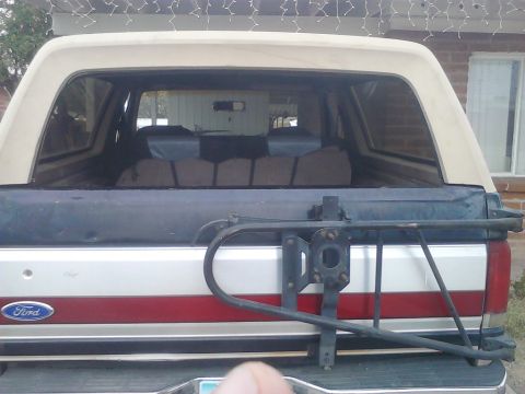 1990 Ford Bronco - Rear view of a 1990 Ford Bronco, showing the spare tire carrier and tan removable top.