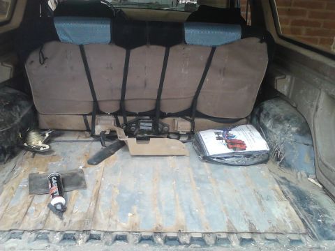 1990 Ford Bronco - The cargo area of a 1990 Ford Bronco shows its folded rear seats and some tools.