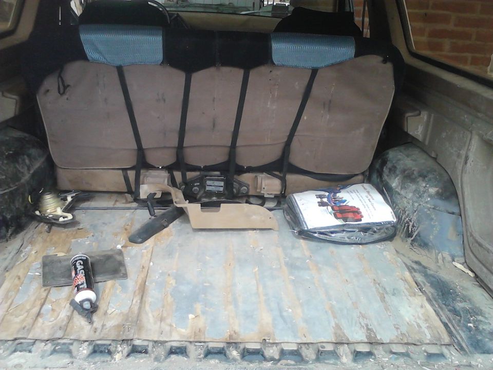 1990 Ford Bronco interior cargo area with folded rear seats, a jack, and a manual