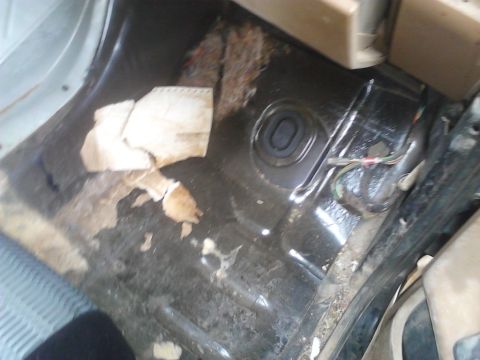1990 Ford Bronco - The interior floor of the vehicle shows significant wear and tear, with torn carpet and exposed metal.