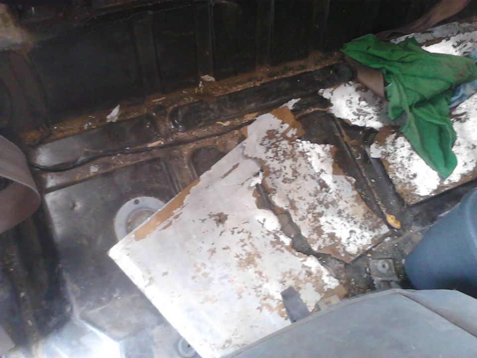 Interior of a vehicle with peeling paint and debris, possibly during restoration