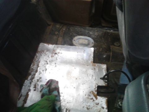 1990 Ford Bronco - The interior floor of a vehicle shows a metal plate installed over a section of the floor, with some rust visible.