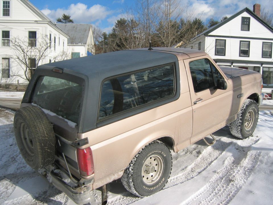 Tan 1996 Ford Bronco in snow, rear quarter view with spare tire