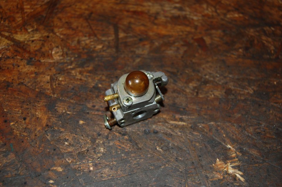 Carburetor with amber primer bulb on wooden surface