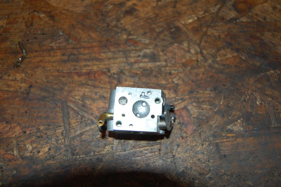 small metal carburetor with brass fitting on a wooden surface