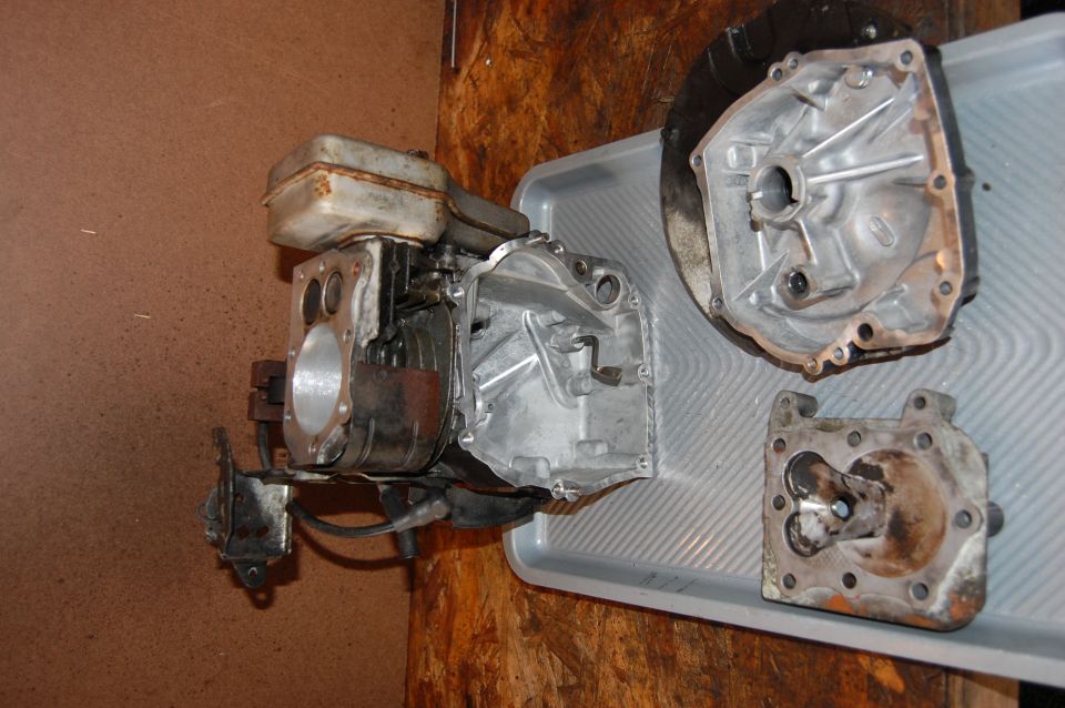 Engine block and two other metal parts laid out on a gray tray