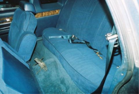 1984 Mercury Grand Marquis - The interior of a car shows blue seats and seatbelts, with a metal object on the floor.