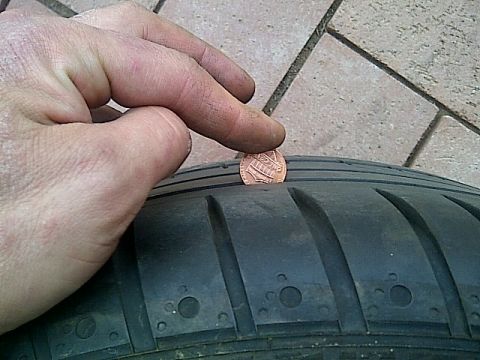 1993 Ford Probe - Checking tire tread depth with a penny. The tire has visible tread wear indicators.
