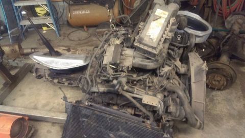 1995 Ford Bronco - A disassembled engine and transmission assembly is shown in a workshop setting.