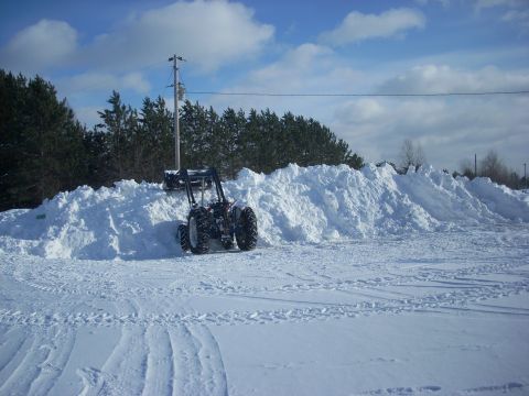 1963 Hummer H3 - A tractor moves snow in a winter scene, with a large pile of snow dominating the landscape.