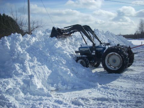 1963 Hummer H3 - Tractor clearing a large pile of snow with its front loader.