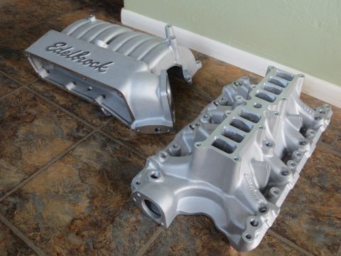 1996 Ford Bronco - Two silver Edelbrock intake manifolds are shown on a tiled floor, likely for an engine build.