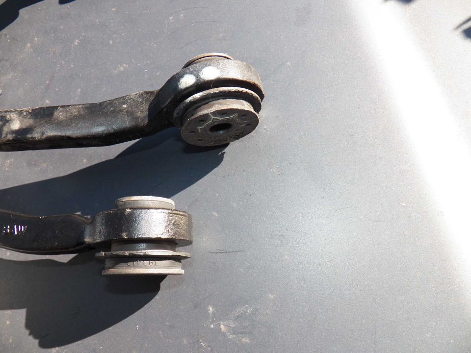 Two car suspension control arm bushings, one with white marks, the other with visible part numbers