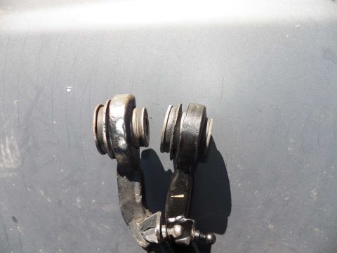 1998 Lincoln Mark VIII - Two black metal front suspension control arms with rubber bushings are shown against a gray background.