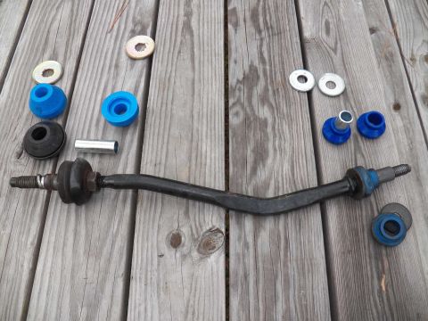 1998 Lincoln Mark VIII - A collection of new suspension parts, including a stabilizer bar and various bushings, are displayed on a weathered wooden surface.