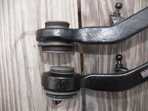 1998 Lincoln Mark VIII - Close-up of two automotive front suspension control arms, possibly for comparison or replacement.
