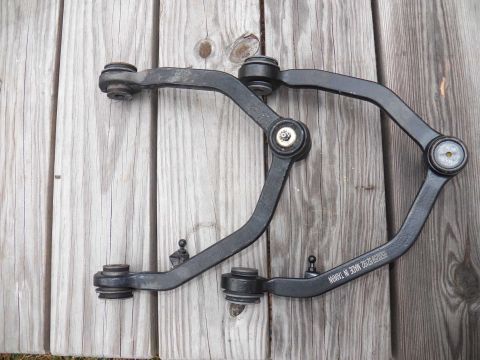 1998 Lincoln Mark VIII - Pair of front suspension control arms, likely aftermarket, shown on a wooden surface. Text indicates they were made in Taiwan.