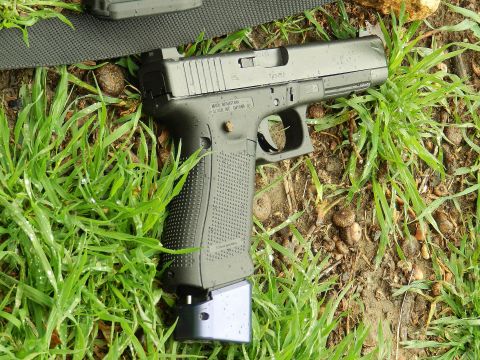 1996 Ford Bronco - Pistol with extended magazine on grass. Text on slide indicates manufacturer and location.