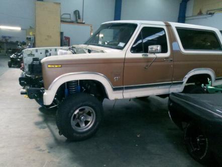 1982 Ford Bronco - This 1980s Ford Bronco is undergoing repairs in a garage, with its hood open and front end partially disassembled.