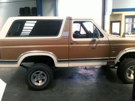 1982 Ford Bronco - Side profile of a two-tone brown and white 1982 Ford Bronco, likely in a garage or workshop.