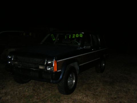 dark SUV with wood paneling and a '$1200' sign in the windshield, parked at night